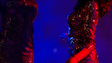 Close-Up-Of-Two-Women's-Torsos-In-Nightclub-Bar-Or-Disco-Dancing-Wearing-Sparkly-Dresses
